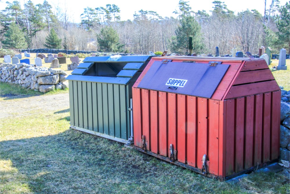 To avfallsdunker på en gravplass i Arendal – den grønne kompostdunken står til venstre og den røde restavfallsdunken med skiltet 